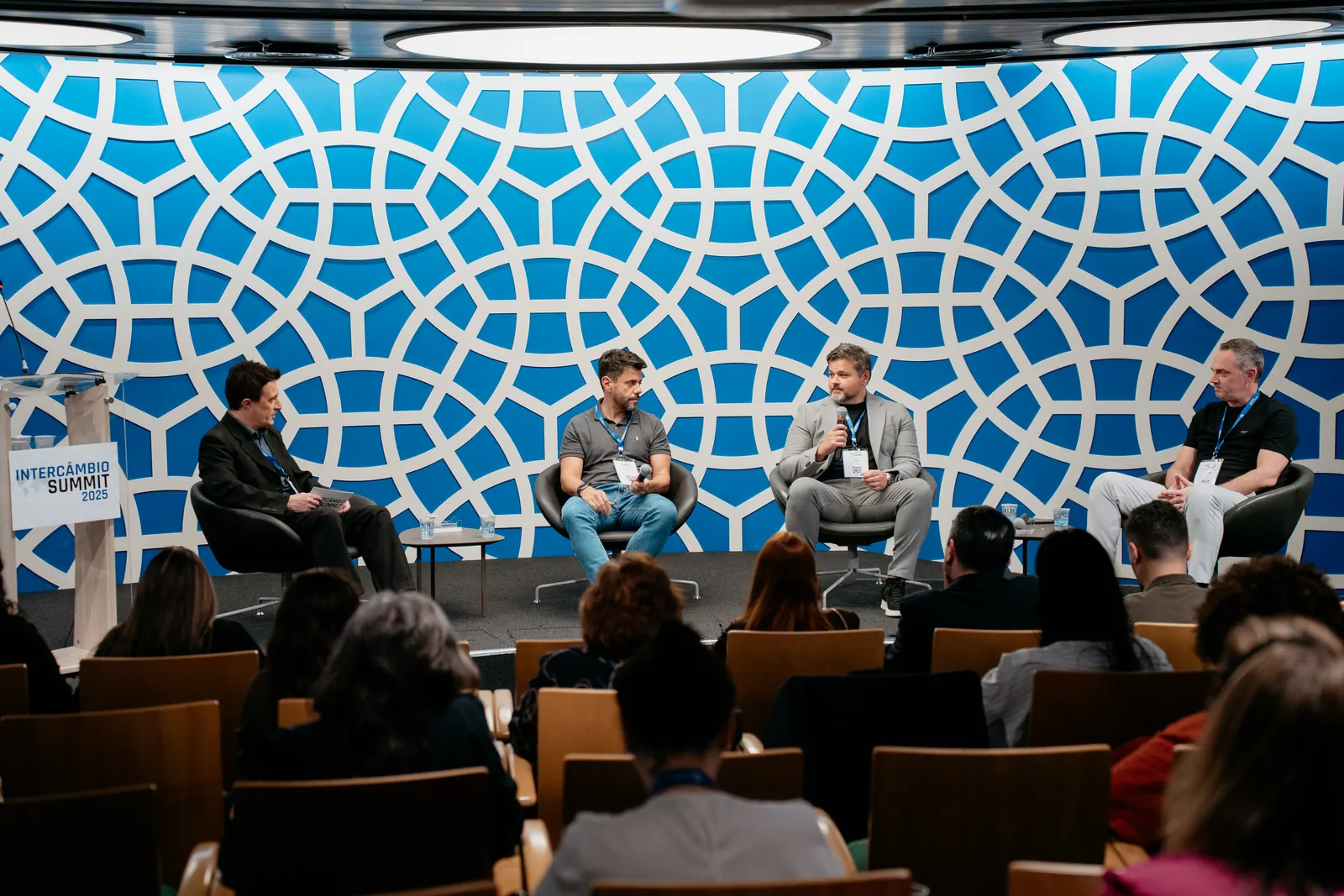 Painel com quatro participantes no palco do Intercâmbio Summit 2025